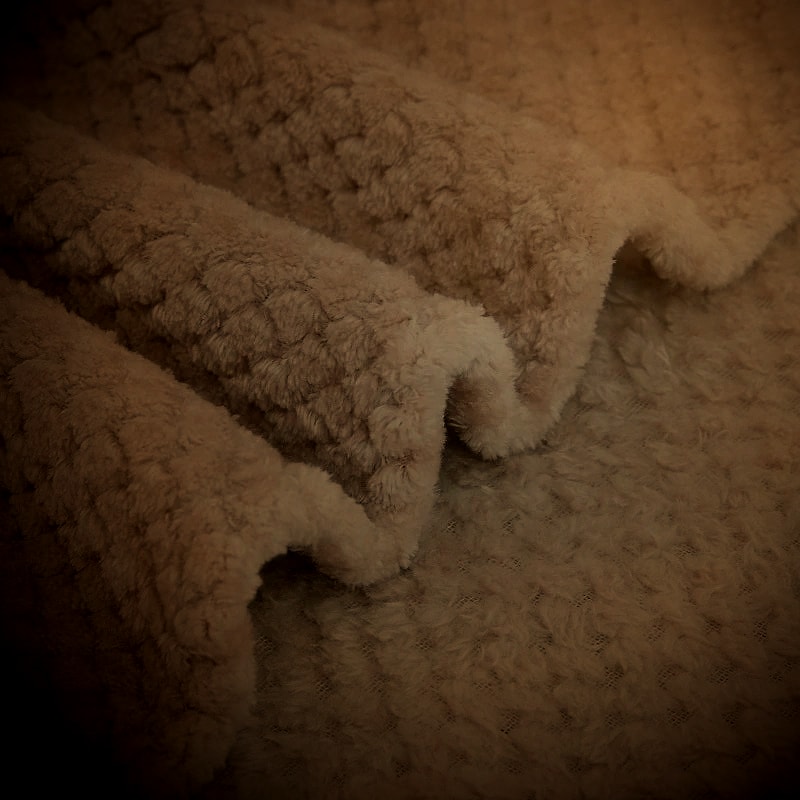 Soft plush blanket folds in warm evening lamplight