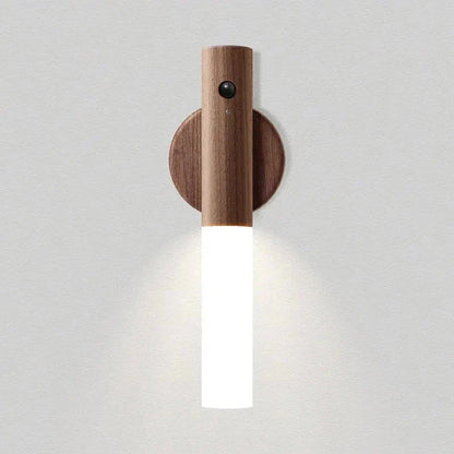 Walnut motion sensor night light glowing on its round wall mount