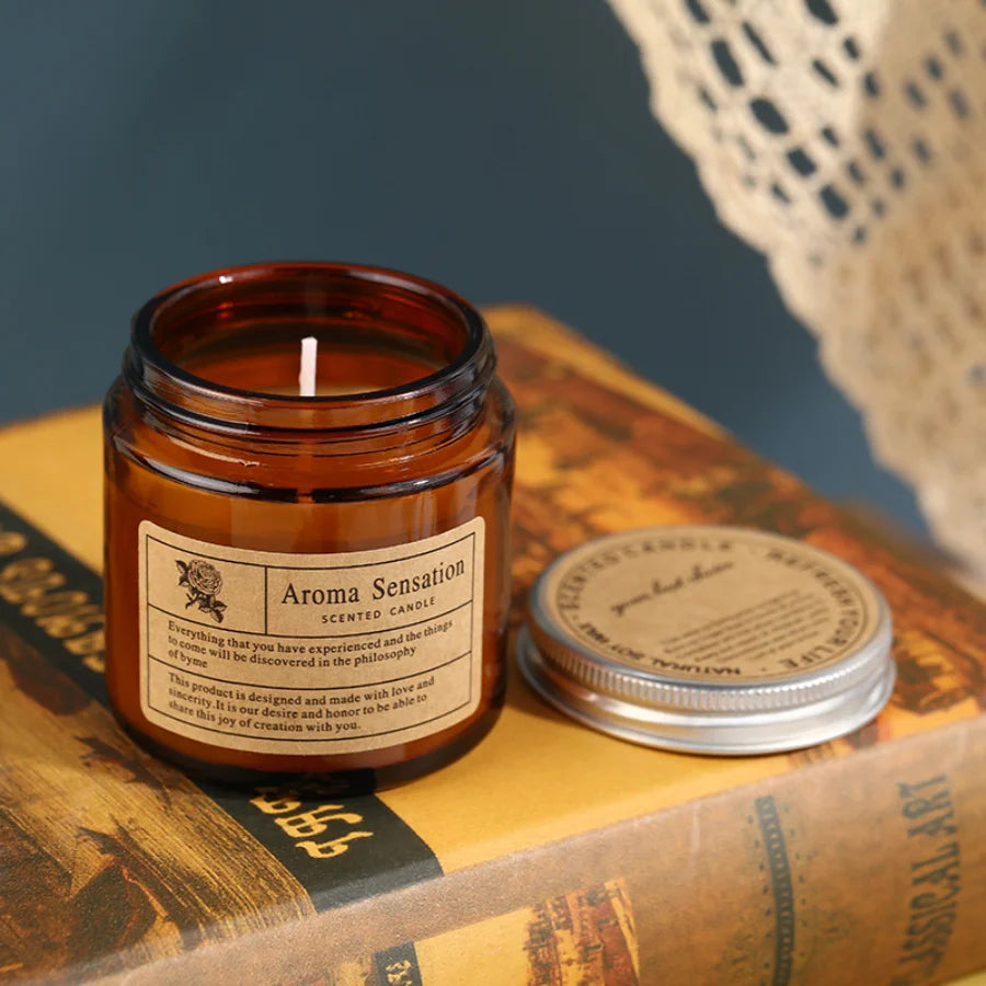 Lit amber glass scented candle on a stack of books