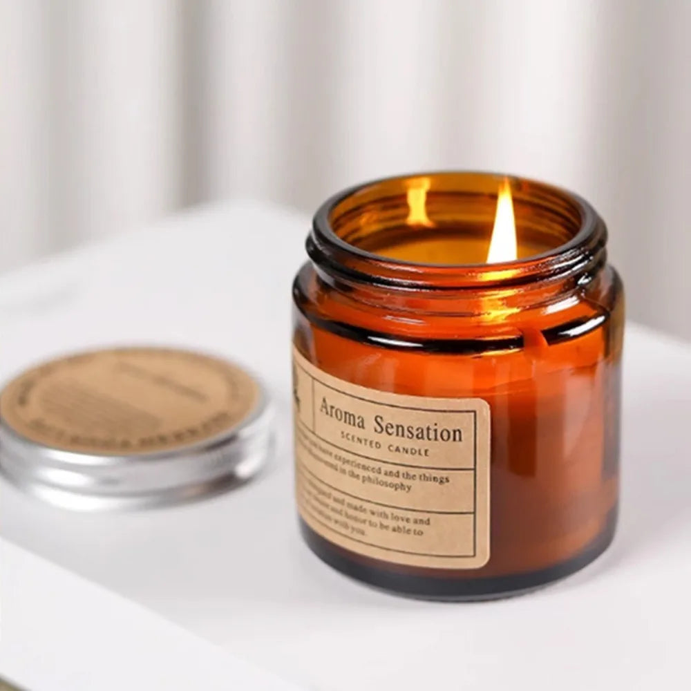 Lit amber glass scented candle beside its metal lid
