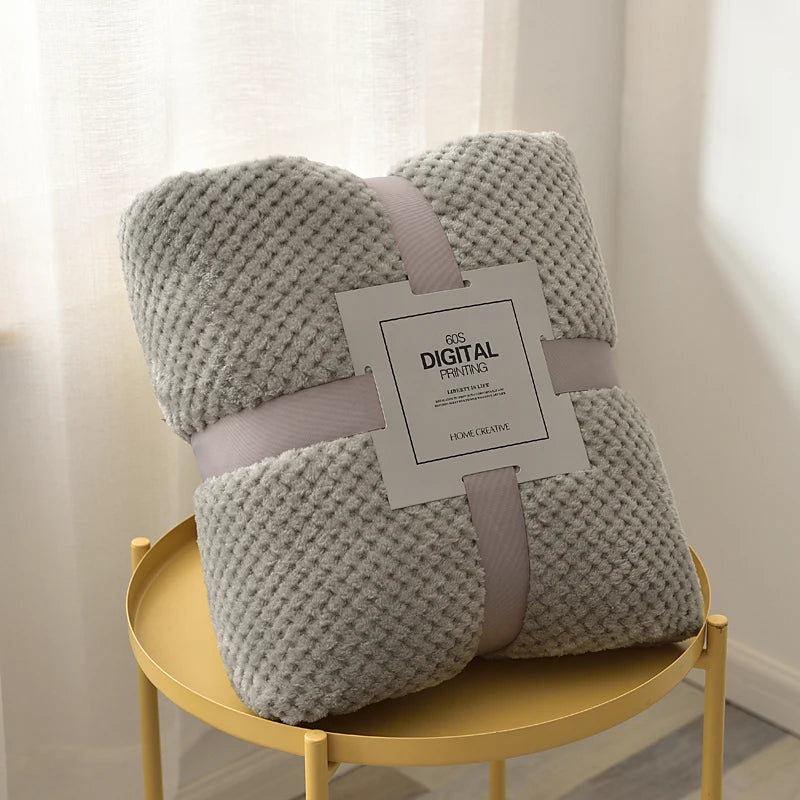 Light grey plush fleece blanket rolled on a side table