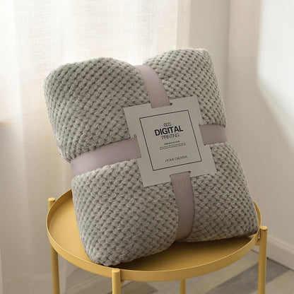 Light grey plush fleece blanket rolled on a side table