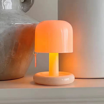 Mushroom night lamp glowing sunset orange beside a vase